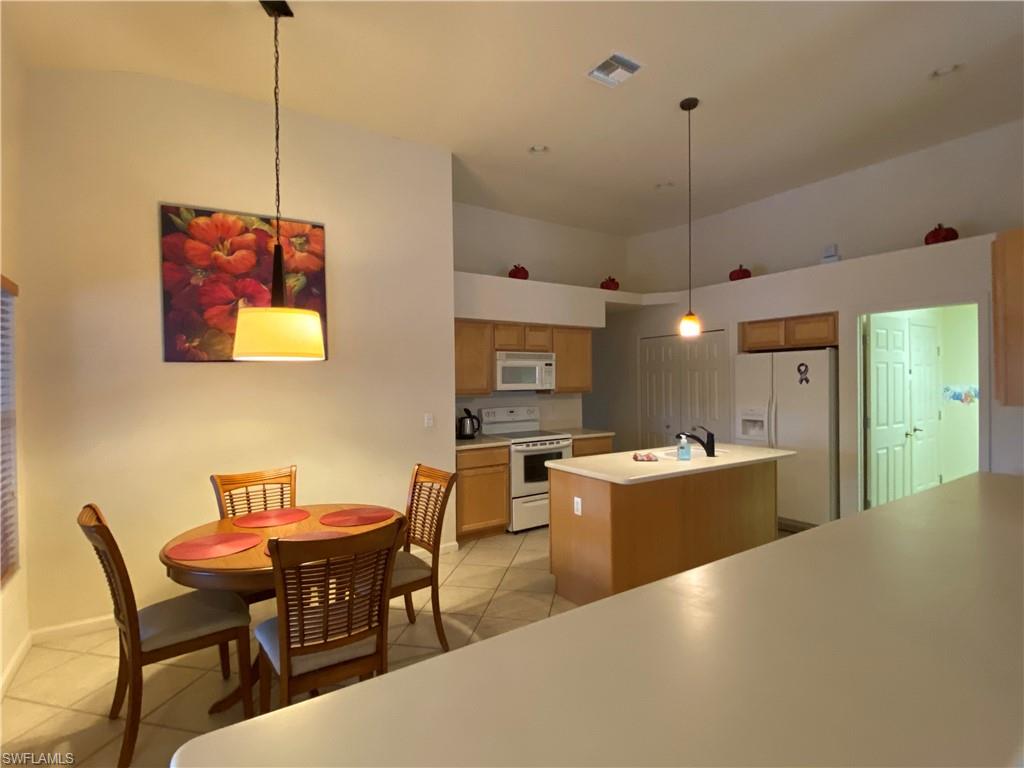 7057 Timberland Circle Naples, FL 34109 - Photo 4 of 22 a view of a dining room and livingroom with furniture wooden floor a chandelier