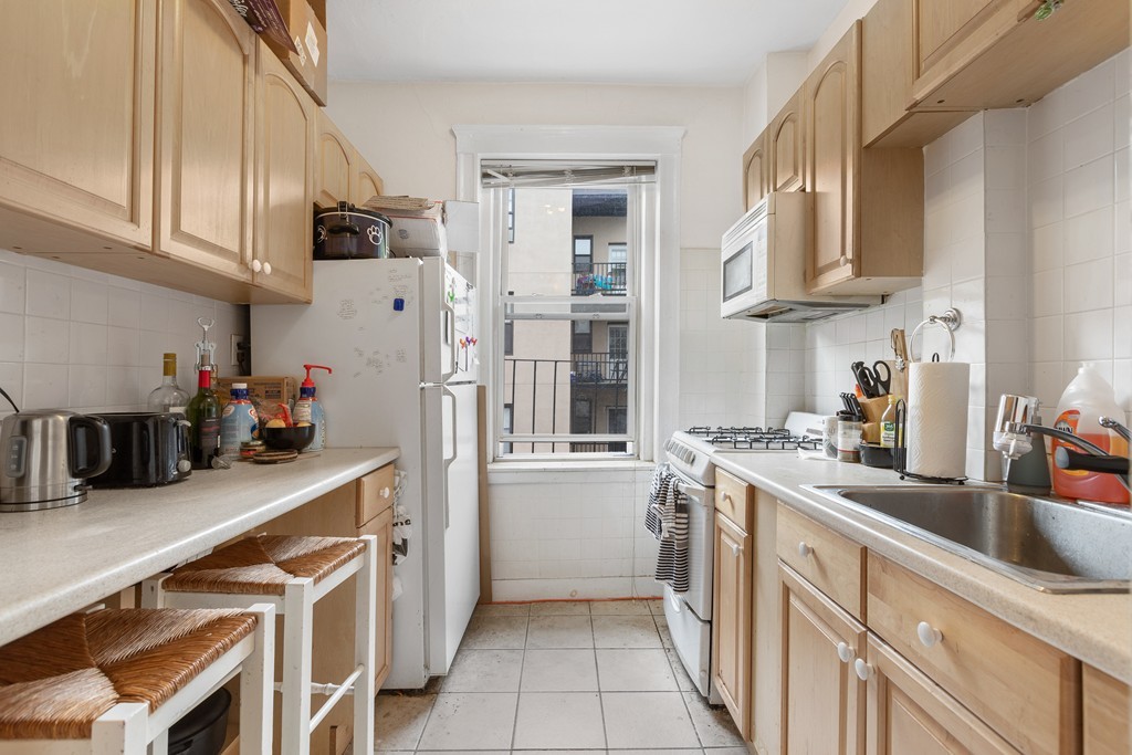316 Summit Avenue, Unit 6 Boston, MA 02135 - Photo 4 of 9 a kitchen with stainless steel appliances granite countertop a refrigerator sink and cabinets