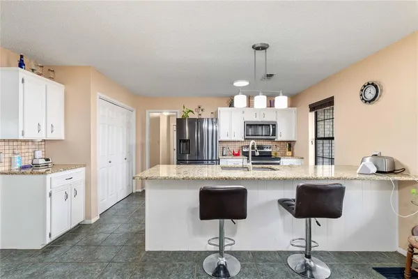 a kitchen with granite countertop a stove a sink dishwasher a dining table and chairs with wooden floor