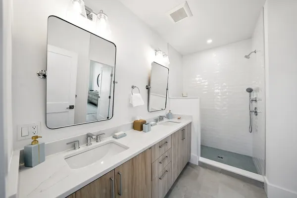 a bathroom with a double vanity sink mirror and shower