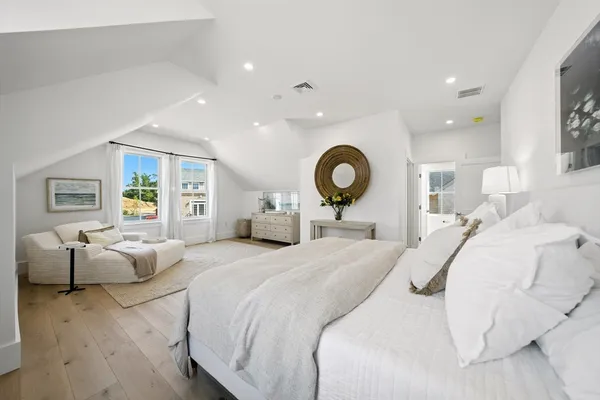a bedroom with a large bed and wooden floor
