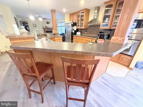 a kitchen with stainless steel appliances wooden floors stove and chairs