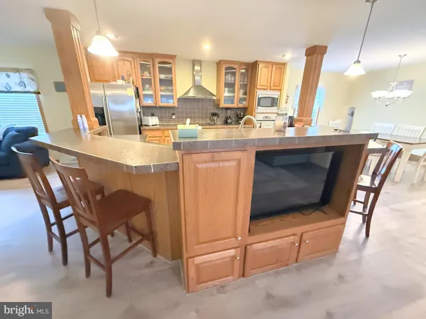 a dining hall with stainless steel appliances kitchen island granite countertop dining table chairs and a large window