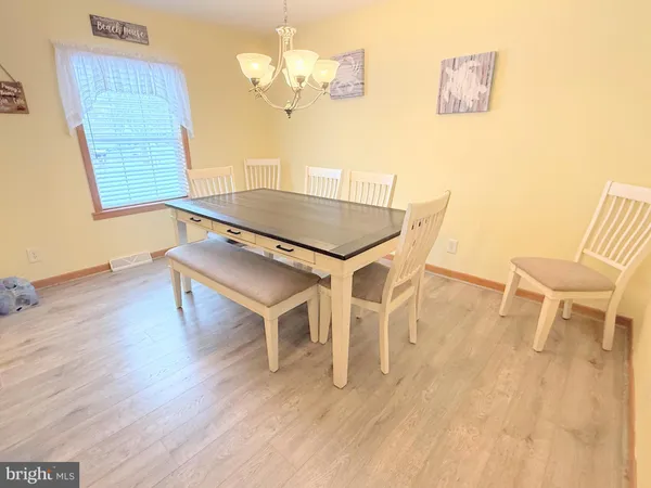 a dining room with wooden floor a chandelier a wooden table and chairs