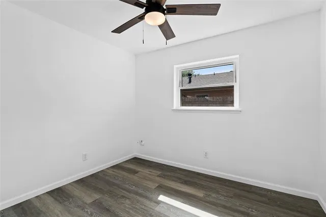 an empty room with wooden floor ceiling fan and windows