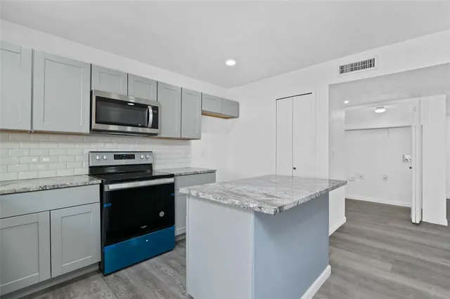 a kitchen with kitchen island granite countertop stainless steel appliances stove microwave and sink