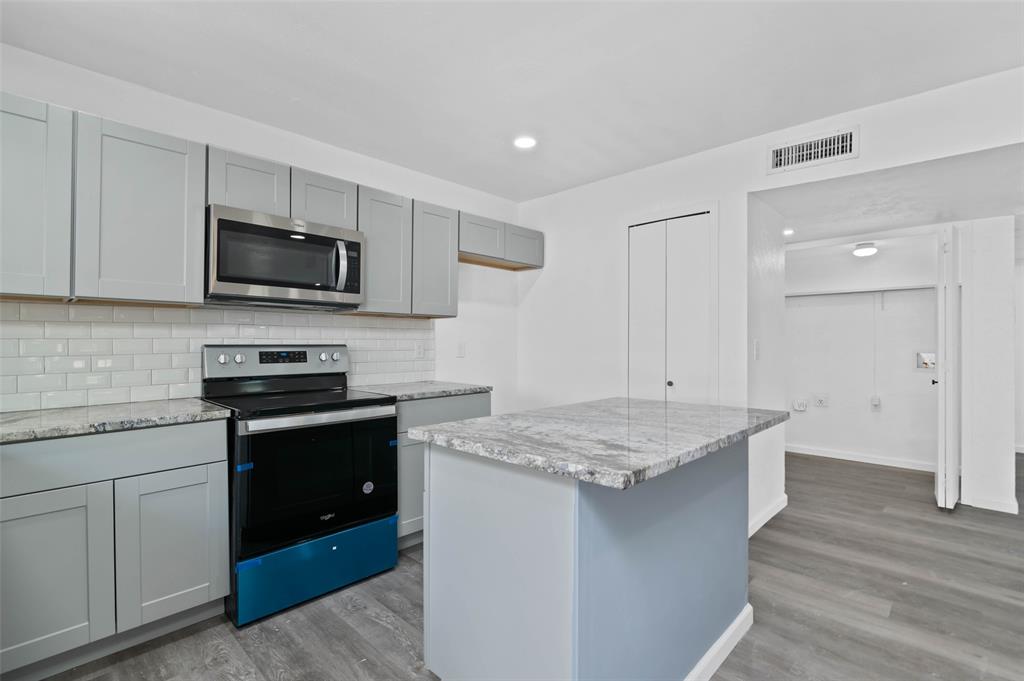 2068 East Peters Colony Road Carrollton, TX 75007 - Photo 6 of 24 a kitchen with kitchen island granite countertop stainless steel appliances stove microwave and sink
