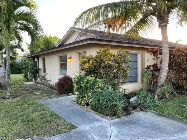 a view of a house with a small yard plants and palm trees