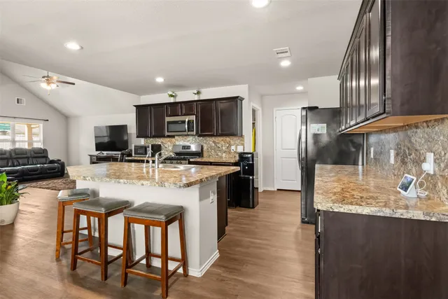 a kitchen with stainless steel appliances granite countertop a stove refrigerator and a sink