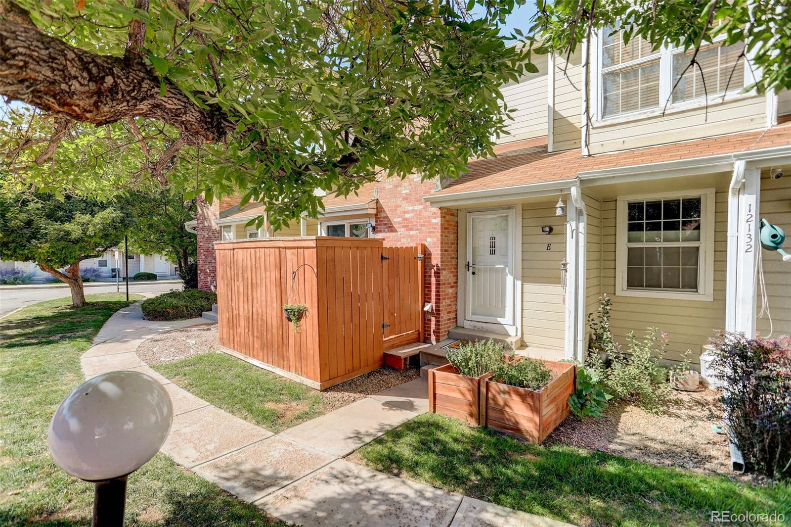 12132 Bannock Circle, Unit E Westminster, CO 80234 - Photo 25 of 26 a view of a backyard with table and chairs and a barbeque with potted plants and a large tree