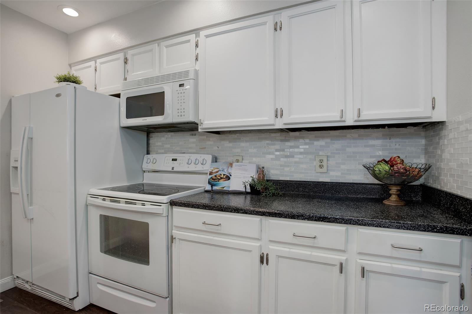12132 Bannock Circle, Unit E Westminster, CO 80234 - Photo 6 of 26 a kitchen with granite countertop white cabinets and white appliances
