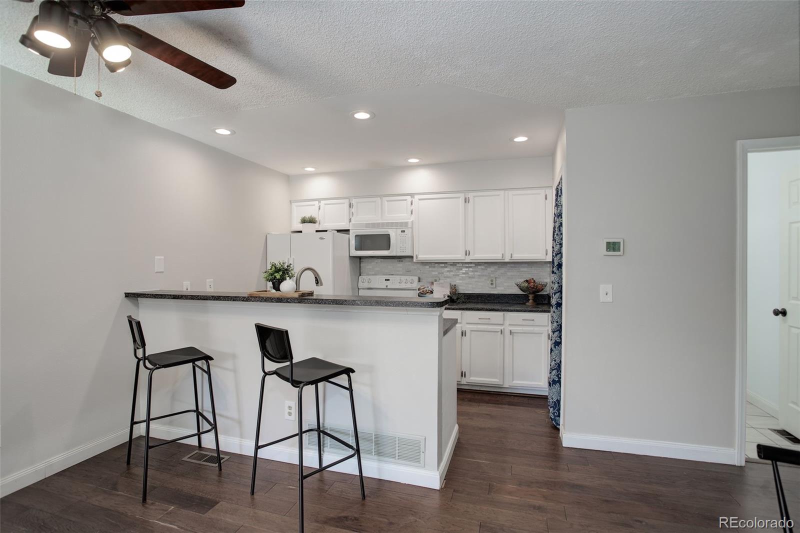 12132 Bannock Circle, Unit E Westminster, CO 80234 - Photo 9 of 26 a kitchen with white cabinets stainless steel appliances and dining table