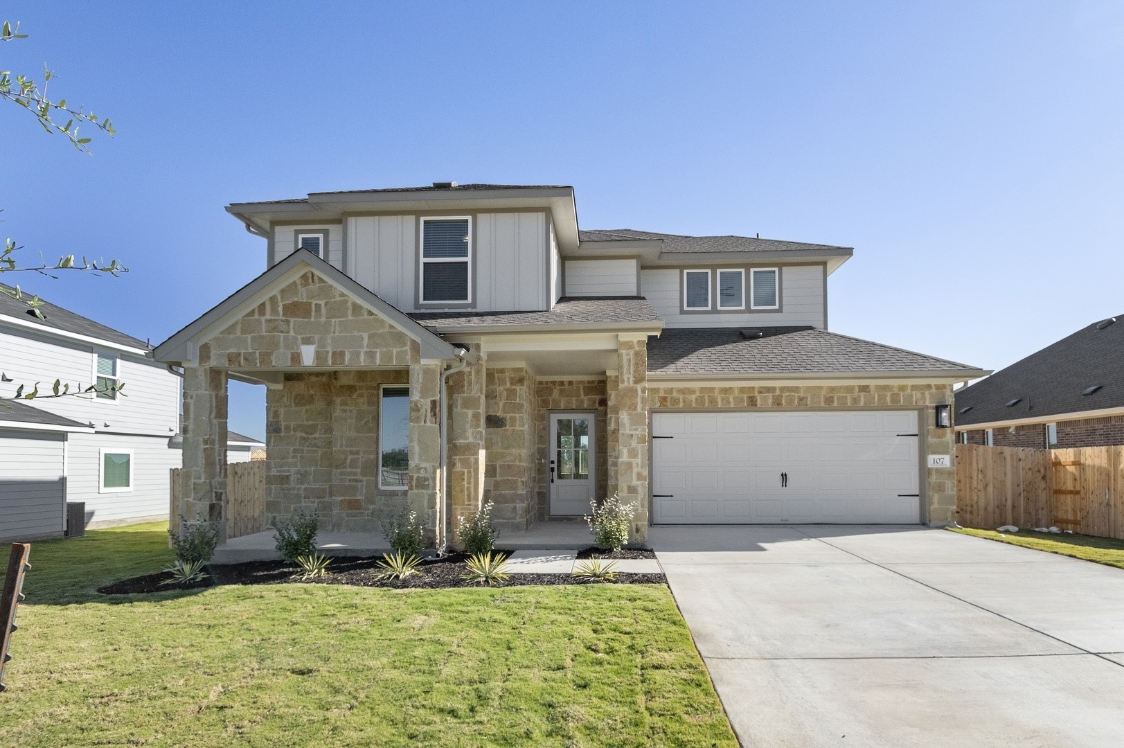 View of front of home with a porch, stone siding, driveway, a garage, and a shingled roof