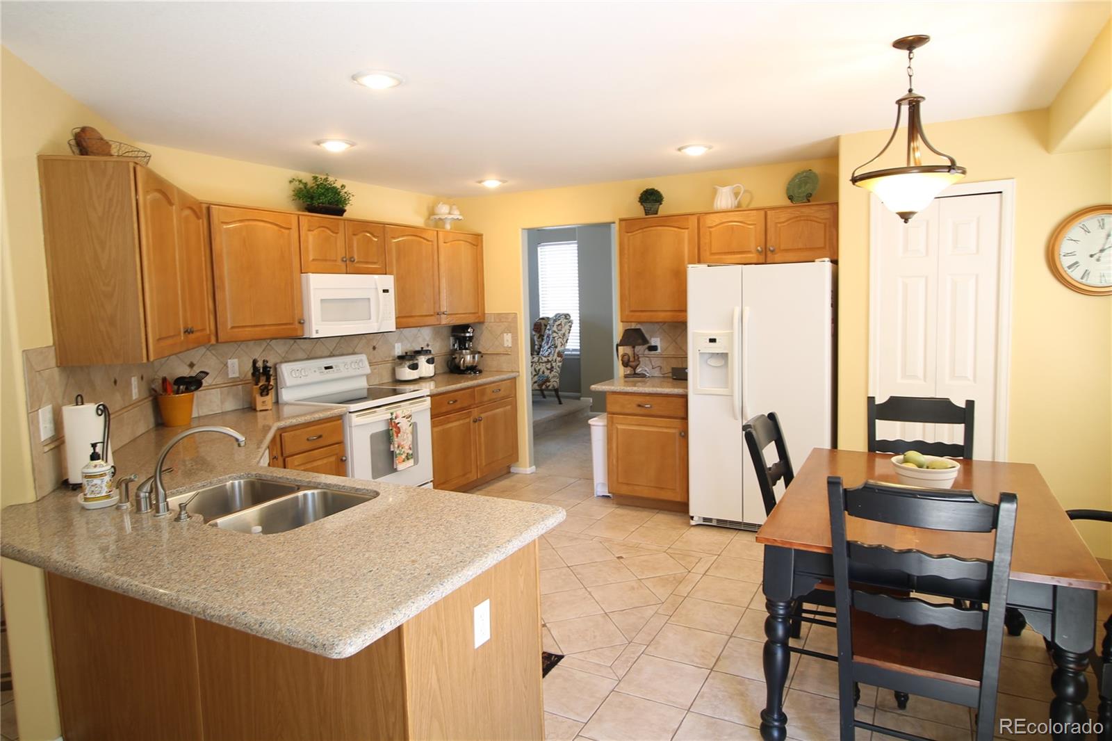 4032 South Killarney Way Aurora, CO 80013 - Photo 5 of 18 a kitchen with wooden cabinets and refrigerator