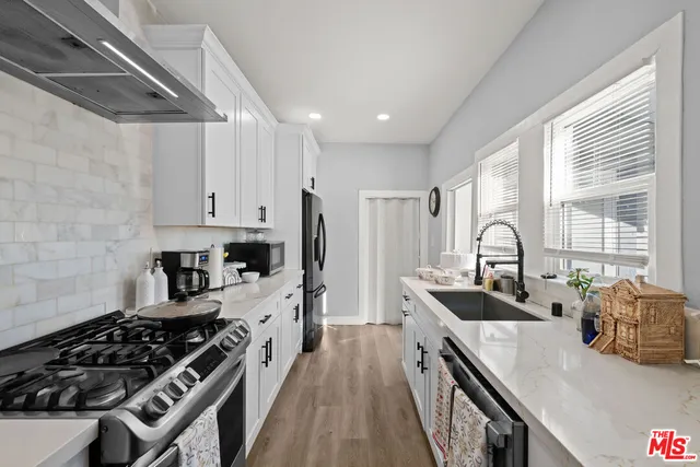 a kitchen with stainless steel appliances a sink a stove and a wooden floors