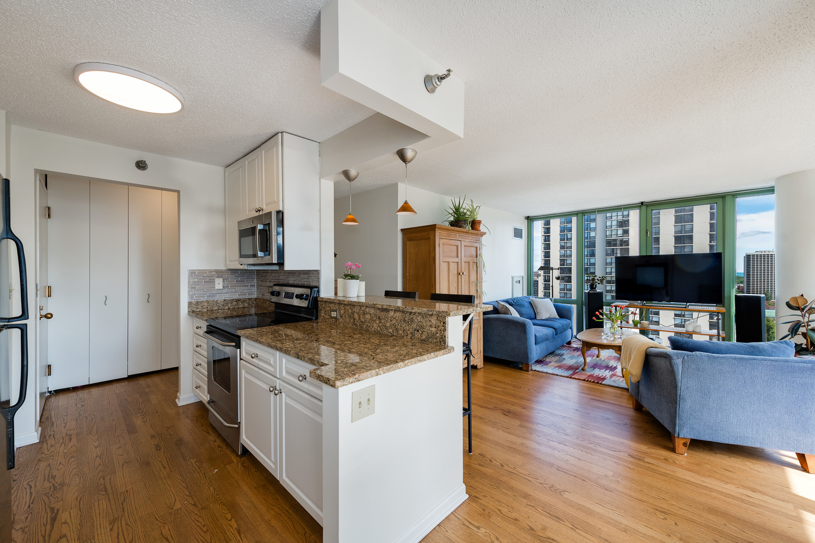 111 West Maple Street, Unit 1601 Chicago, IL 60610 - Photo 11 of 24 a kitchen with stainless steel appliances granite countertop a stove top oven a sink dishwasher a dining table and chairs with wooden floor