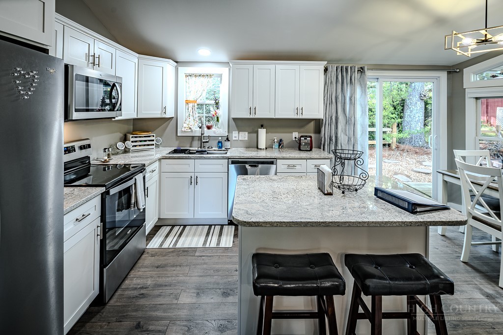 88 Trillium Road Newland, NC 28657 - Photo 22 of 44 a kitchen with stainless steel appliances granite countertop a stove top oven a sink dishwasher and white cabinets with wooden floor