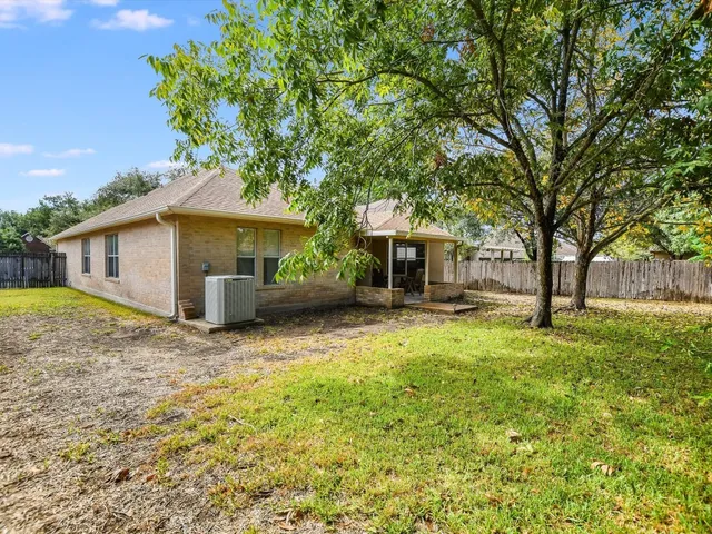 a backyard of a house with table and chairs under an umbrella