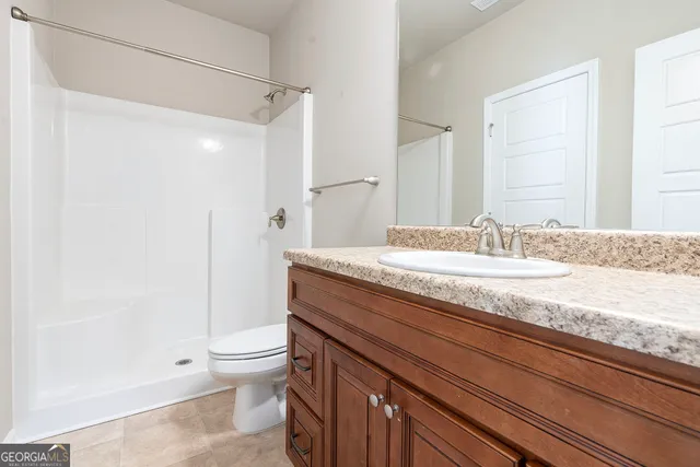 a bathroom with a granite countertop sink a toilet and a shower