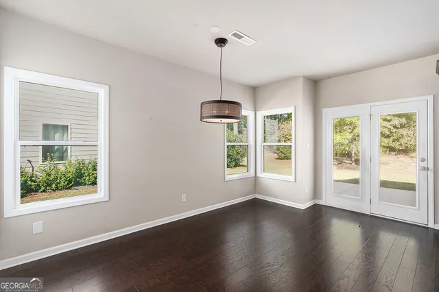 a view of a room with wooden floor ceiling fan and windows