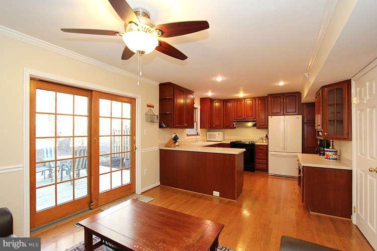11525 Pine Cone Court Reston, VA 20191 - Photo 12 of 30 a large kitchen with stainless steel appliances kitchen island granite countertop a refrigerator a stove a sink and a dining table with wooden floor