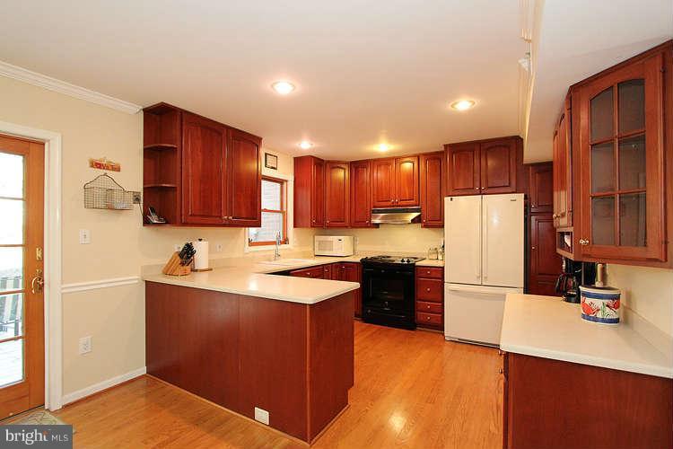 11525 Pine Cone Court Reston, VA 20191 - Photo 10 of 30 a kitchen with kitchen island granite countertop wooden cabinets and a refrigerator