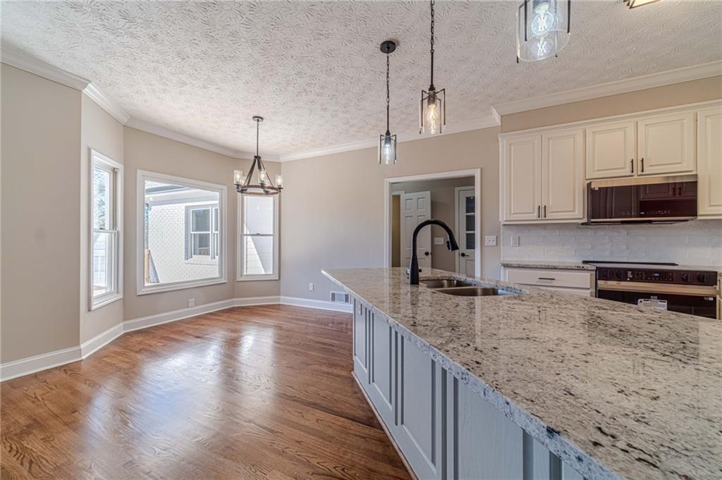 710 Youth Jersey Road Monroe, GA 30655 - Photo 11 of 53 a kitchen with granite countertop a stove a sink dishwasher a microwave oven with cabinets and wooden floor
