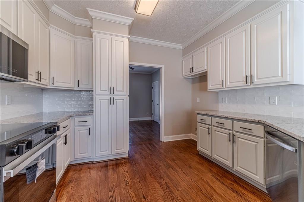 710 Youth Jersey Road Monroe, GA 30655 - Photo 16 of 53 a kitchen with granite countertop wooden floors and white stainless steel appliances