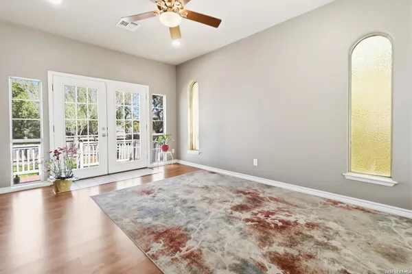an empty room with wooden floor and windows