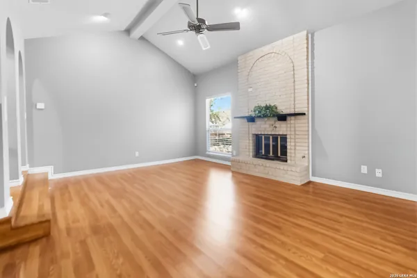 an empty room with wooden floor fireplace and windows