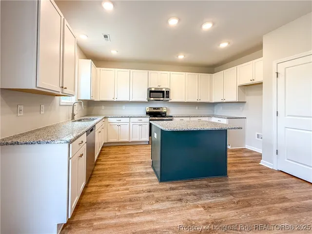 a kitchen with stainless steel appliances granite countertop a stove a sink and white cabinets