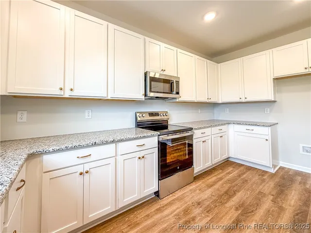 a kitchen with stainless steel appliances granite countertop a stove a sink and a microwave