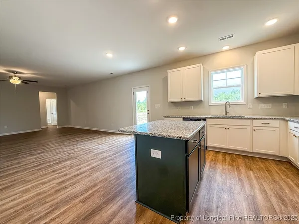 a kitchen with stainless steel appliances granite countertop a stove a sink and white cabinets