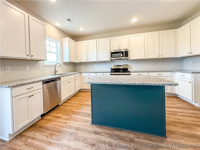 a kitchen with granite countertop white cabinets and stainless steel appliances