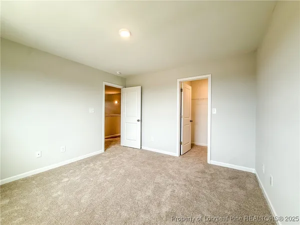 a view of a hallway with white walls and a refrigerator