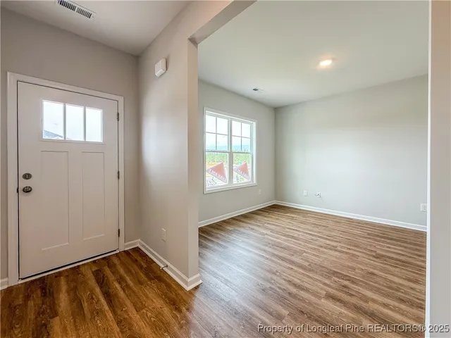an empty room with wooden floor and windows