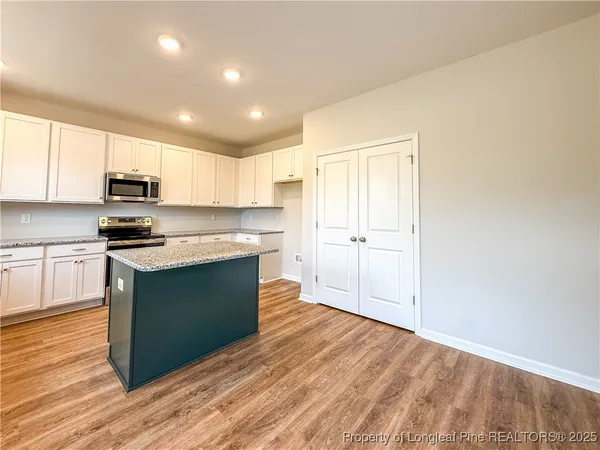 a kitchen with kitchen island granite countertop wooden floors stainless steel appliances a sink and a counter space