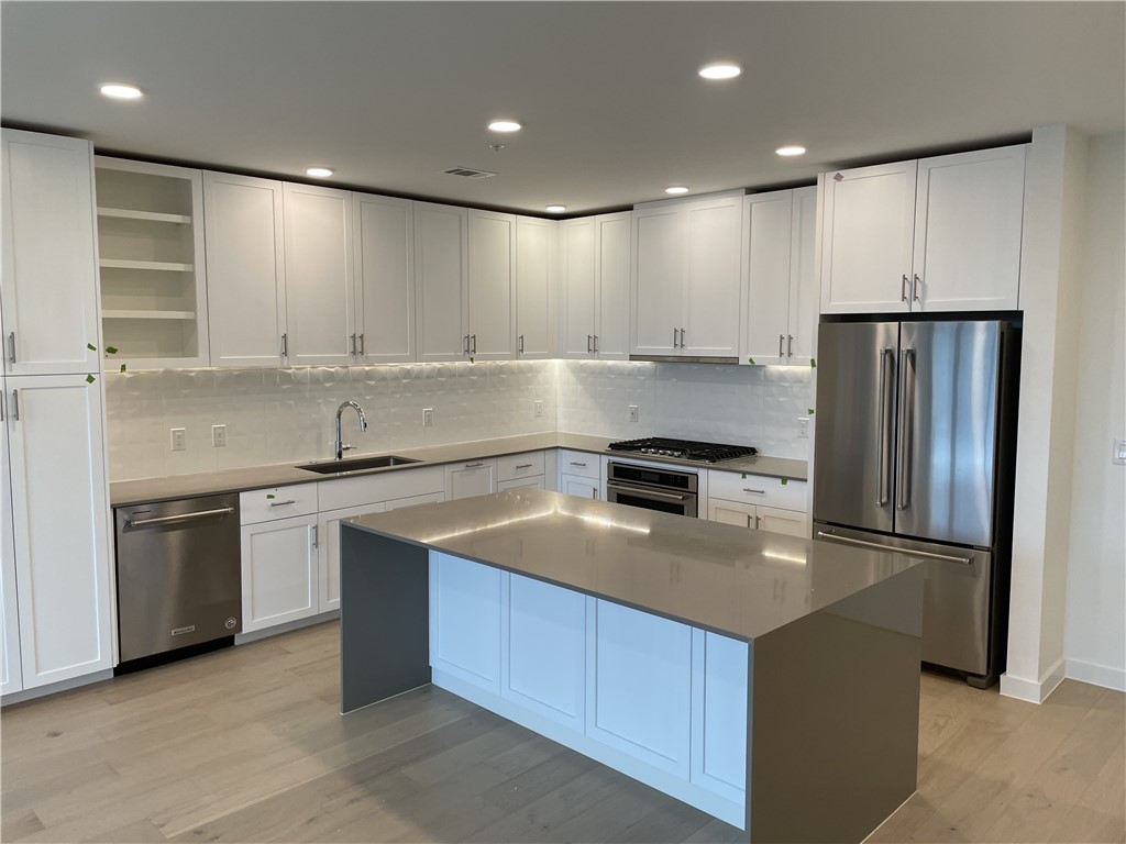 a kitchen with kitchen island granite countertop a sink and refrigerator