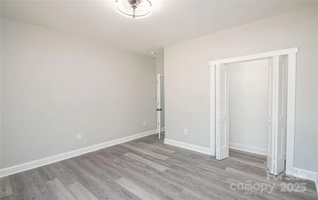 a view of an empty room with wooden floor and closet