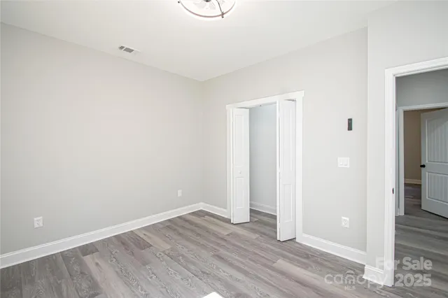 a view of an empty room with wooden floor and a bathroom