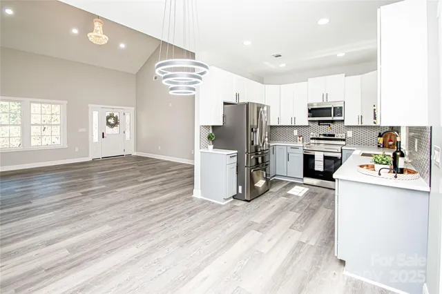 a kitchen with stainless steel appliances a stove top oven a refrigerator cabinets and wooden floor