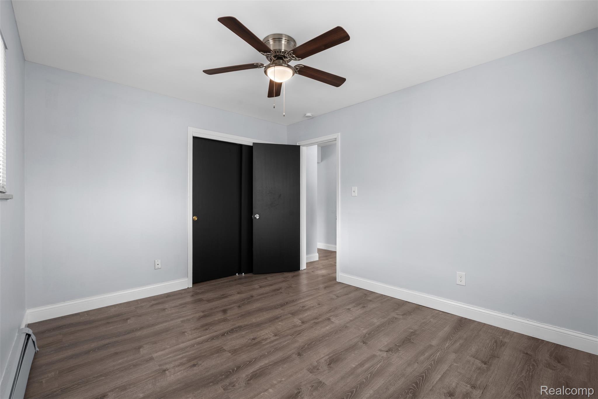3931 Devon Road Royal Oak, MI 48073 - Photo 8 of 11 Unfurnished bedroom with baseboard heating, ceiling fan, and dark wood-type flooring