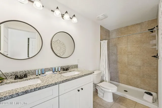 a bathroom with a granite countertop double vanity sink and mirror