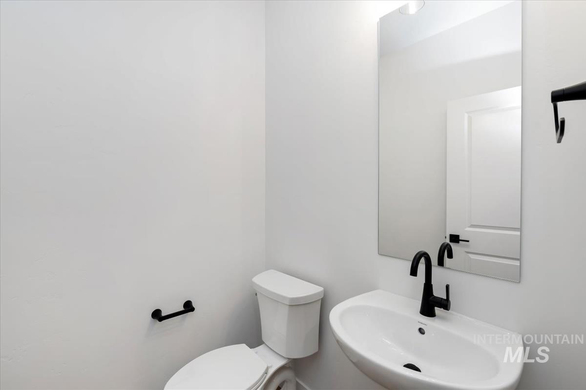 768 South Calhoun Lane Star, ID 83669 - Photo 31 of 36 Contemporary powder room featuring a wall-mounted sink with matte black faucet, rectangular mirror, and white toilet