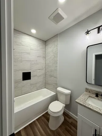 a bathroom with a granite countertop toilet a sink and bathtub