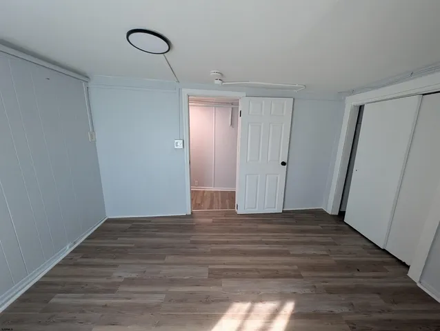 a view of an empty room with wooden floor and closet