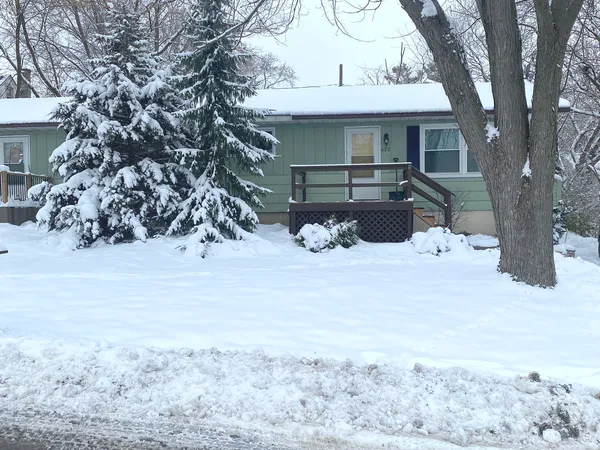 a front view of a house with a yard covered with snow