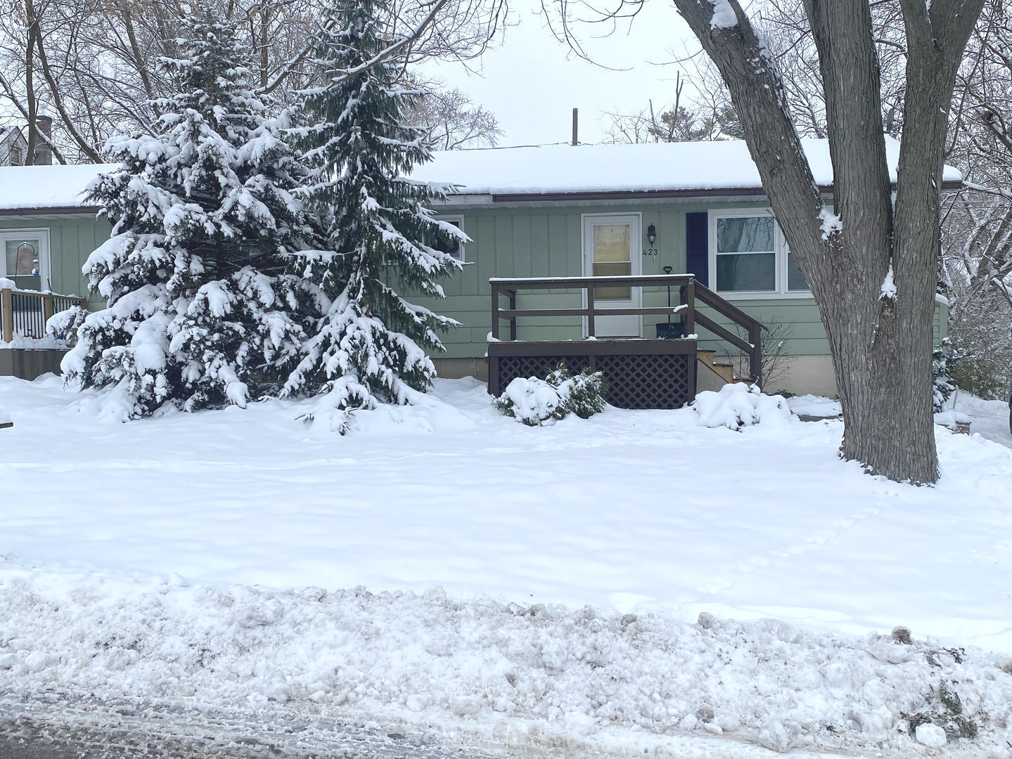 a front view of a house with a yard covered with snow