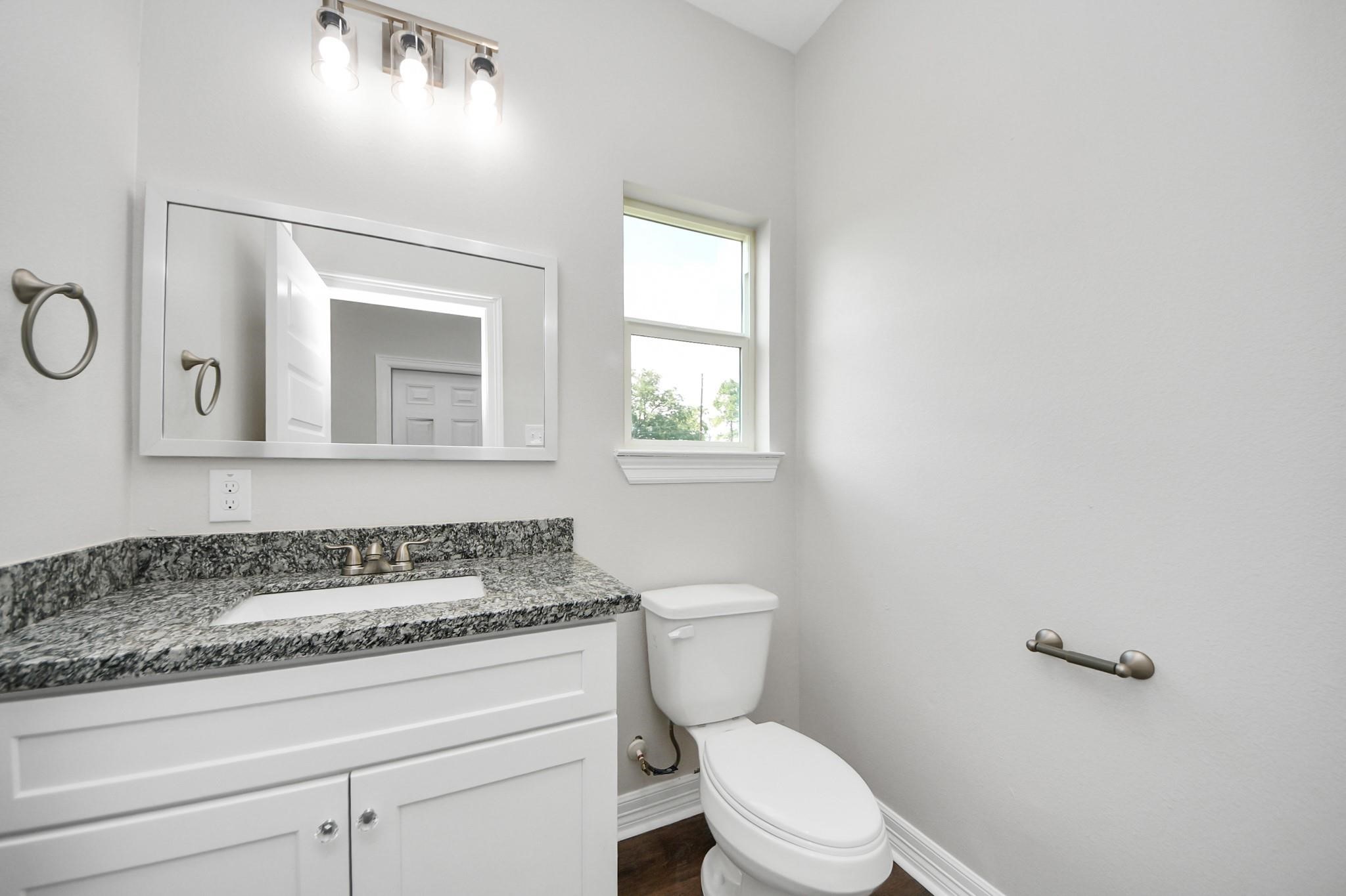 418 North 4th Street Beasley, TX 77417 - Photo 15 of 29 a bathroom with a granite countertop toilet sink and mirror