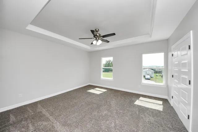 an empty room with windows and ceiling fan